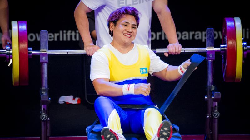 Raushan Koishibayeva smiling while sitting on the bench after her lift